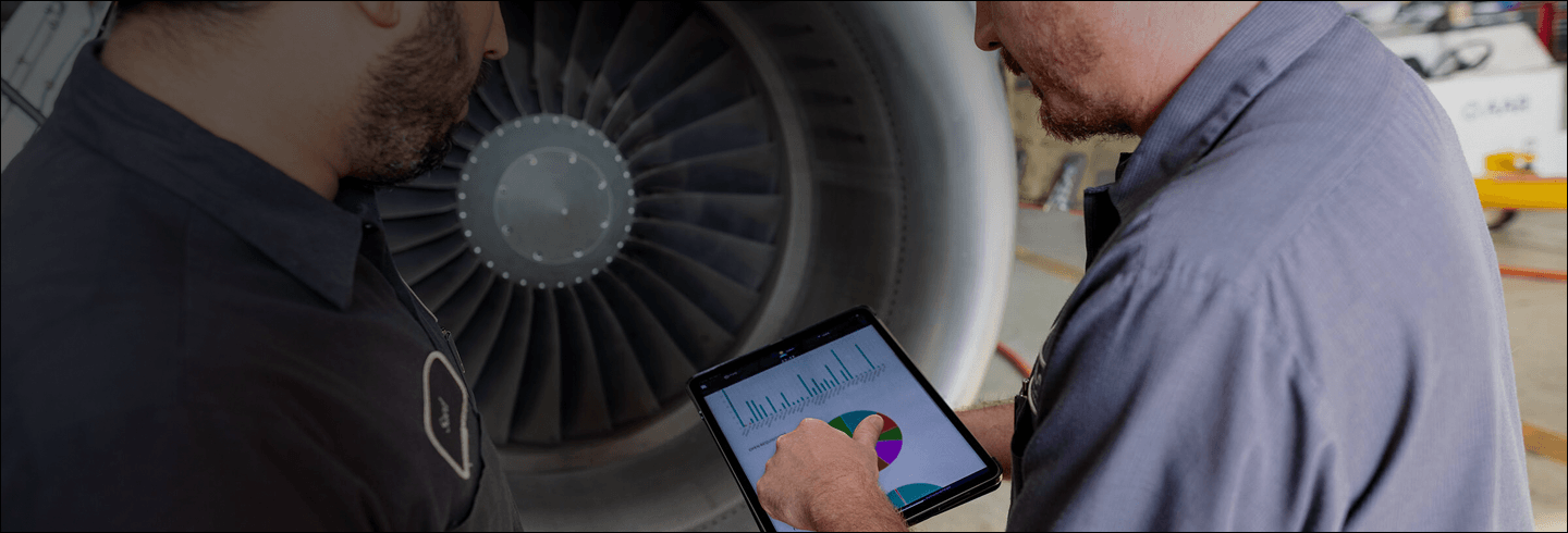 Employees on a tablet in front of a plane
